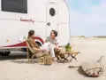 Para na plaży przy kamperze, relaksująca rozmowa. To właśnie karawaning co to – wolność i przygoda.
