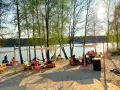 Relaks na plaży nad jeziorem, idealne miejsce na camping Polska. Ludzie odpoczywają na leżakach i paletach pod namiotami.