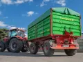 Czerwony traktor z zieloną przyczepą. Dowiedz się, jakich przyczep nie trzeba rejestrować, by ułatwić sobie pracę w gospodarstwie.