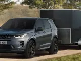 Szary Land Rover Discovery Sport z przyczepą o masie 2000 kg jedzie po leśnej drodze.