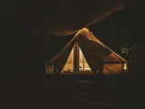 Nocą oświetlony namiot na darmowych miejscach biwakowych. Ciepłe światło wydobywa się z wnętrza, tworząc przytulną atmosferę.