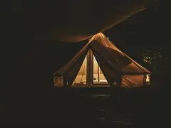 Nocą oświetlony namiot na darmowych miejscach biwakowych. Ciepłe światło wydobywa się z wnętrza, tworząc przytulną atmosferę.