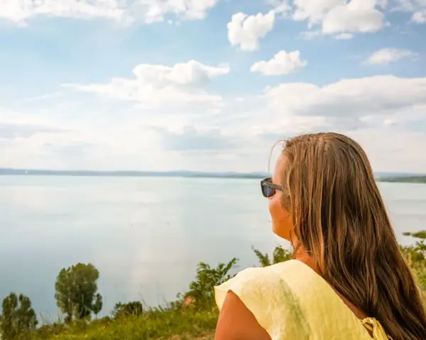 Kobieta w okularach podziwia rozległy Balaton, zachwycona czystością wody i błękitem nieba.