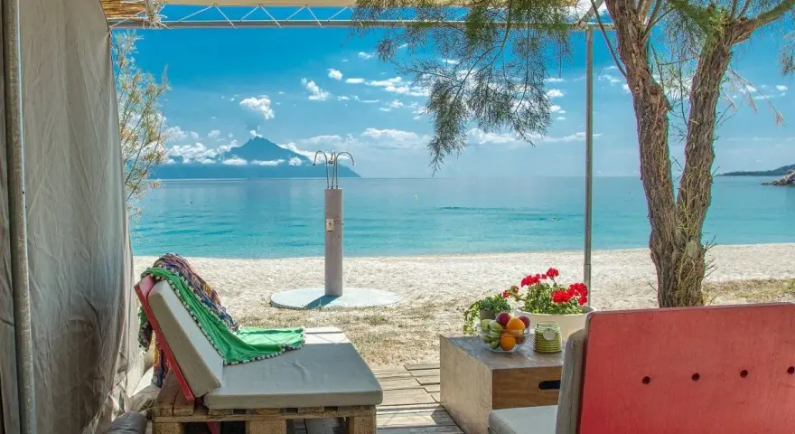 Relaks przy plaży w Armenistis Camping. Leżaki, stolik z owocami i widok na turkusowe morze.