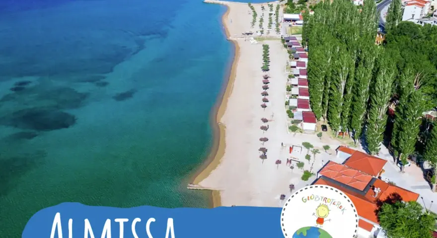 Widok z lotu ptaka na plażę i kemping Almissa (dawniej Galeb) w Chorwacji. Turkusowe morze, piaszczysta plaża, rzędy domków i wysokie drzewa.