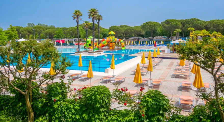 Słoneczny dzień w Portofelice Camping Village. Baseny, zjeżdżalnie i leżaki czekają na gości.