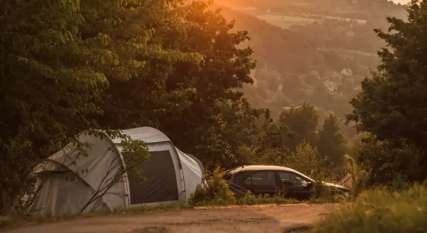 Namiot i samochód na tle malowniczego krajobrazu o zachodzie słońca. Idealne miejsce na **camping Kraków**.