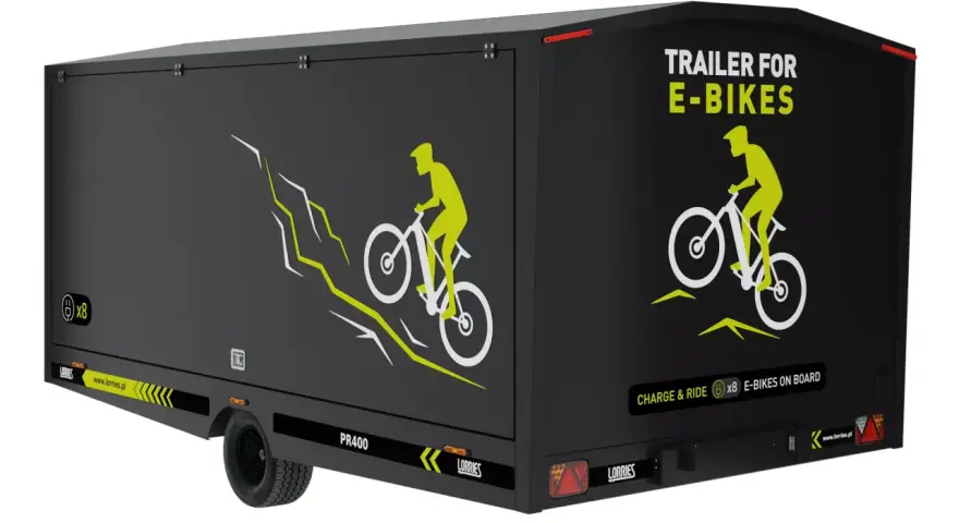 Czarna rowerowa przyczepa kempingowa z grafiką rowerzysty na górskim szlaku. Napis "TRAILER FOR E-BIKES" i "CHARGE & RIDE x8 E-BIKES ON BOARD".