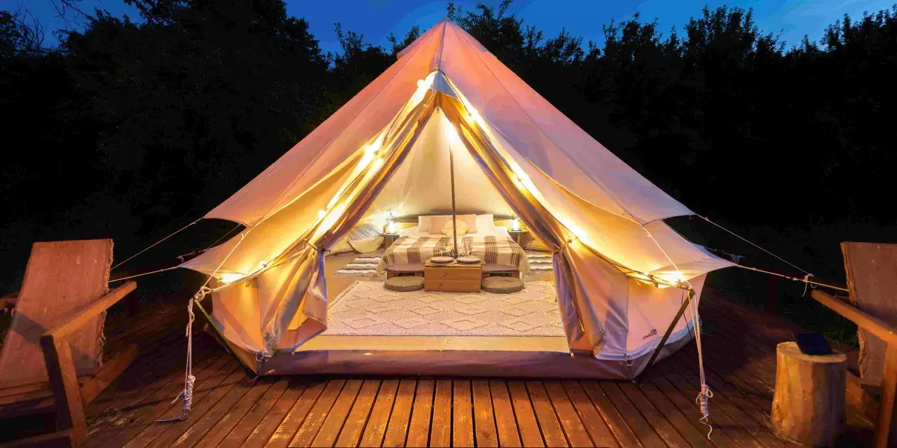 Glamping co to? Luksusowy namiot z wygodnym łóżkiem i oświetleniem, gotowy na nocleg w naturze.