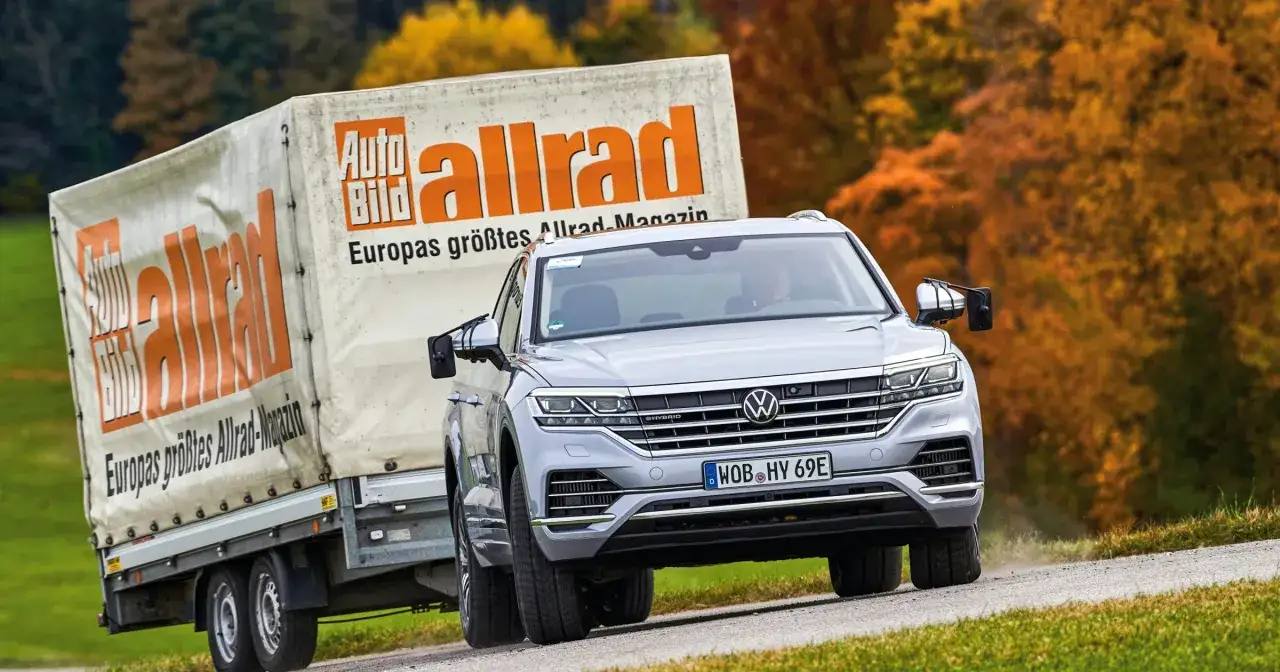 Srebrny Volkswagen Touareg holuje przyczepę z logo