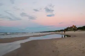 Zachód słońca nad morzem w kurorcie niedaleko Lęborka. Piękne, pastelowe niebo odbija się w wodzie na plaży.