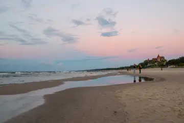 Zachód słońca nad morzem w kurorcie niedaleko Lęborka. Piękne, pastelowe niebo odbija się w wodzie na plaży.