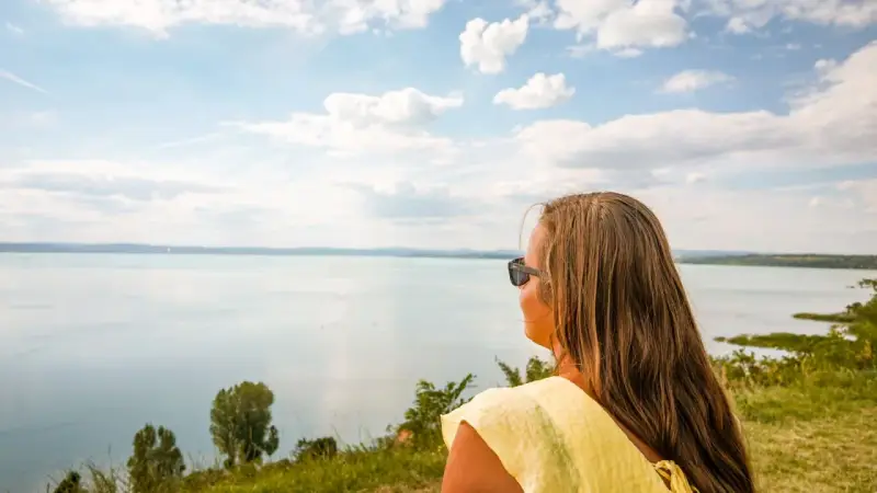 Kobieta w okularach podziwia rozległy Balaton, zachwycona czystością wody i błękitem nieba.